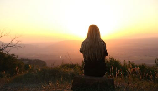 Femme sur colline au coucher de soleil